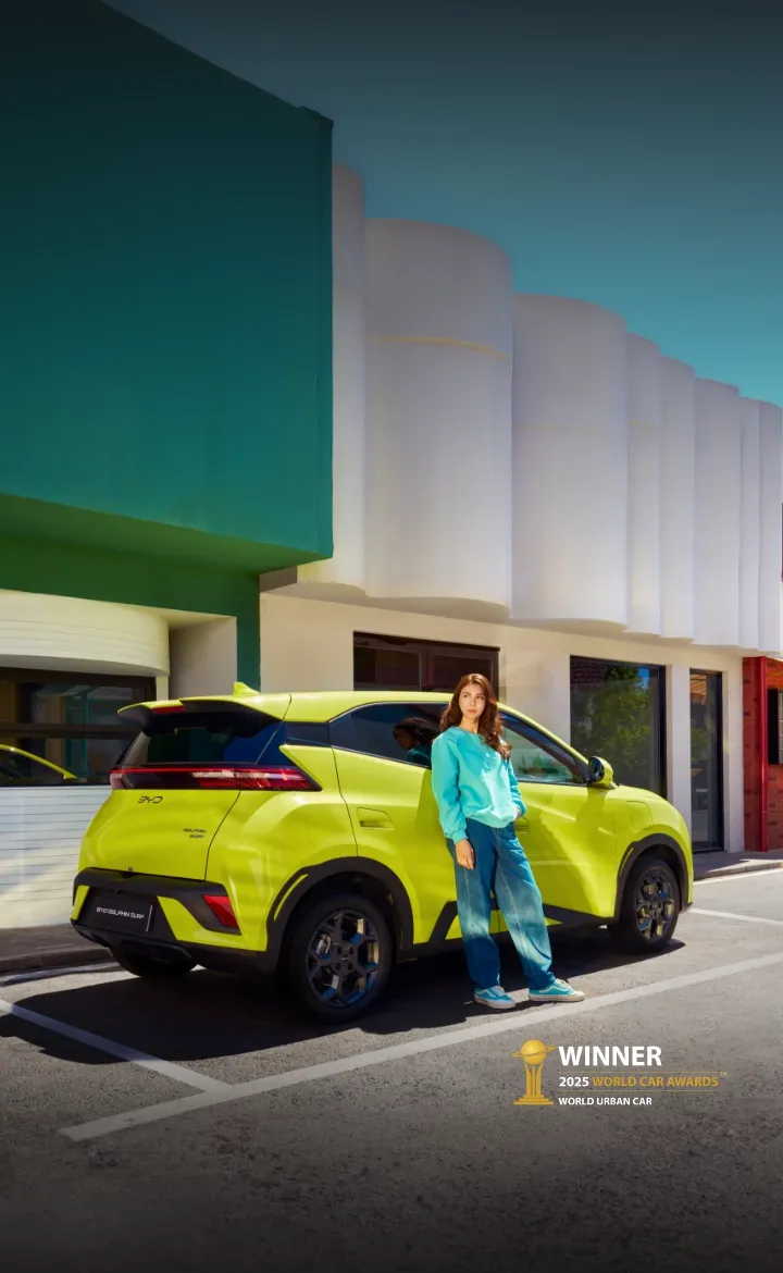 BYD DOLPHIN SURF estacionado com mulher encostada ao carro 