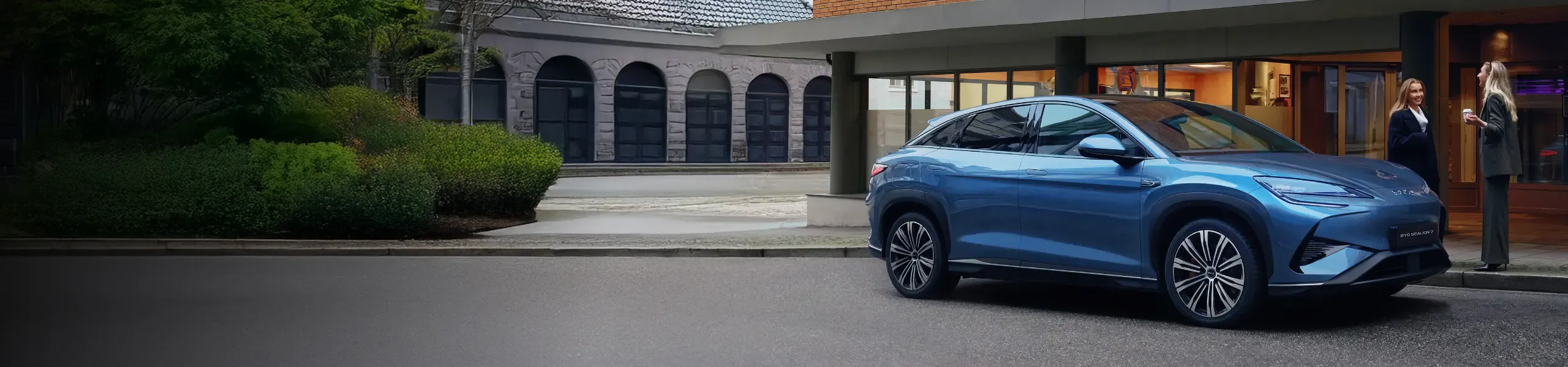 BYD SEALION 7 estacionado na rua e duas mulheres a conversar ao seu lado