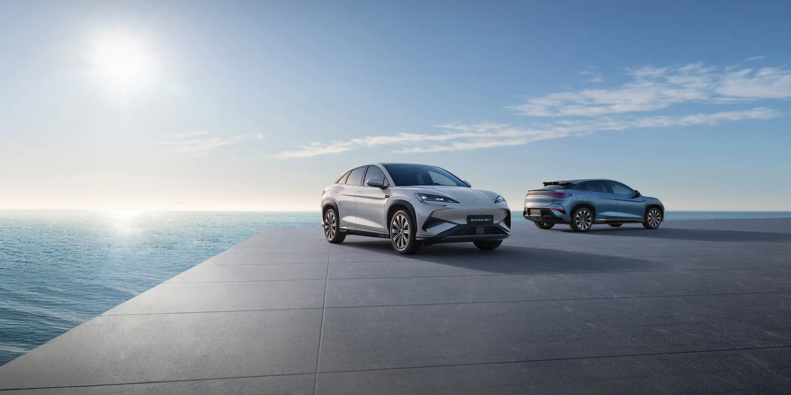 Dois BYD's SEALION 7 parados numa plataforma com vista para o mar
