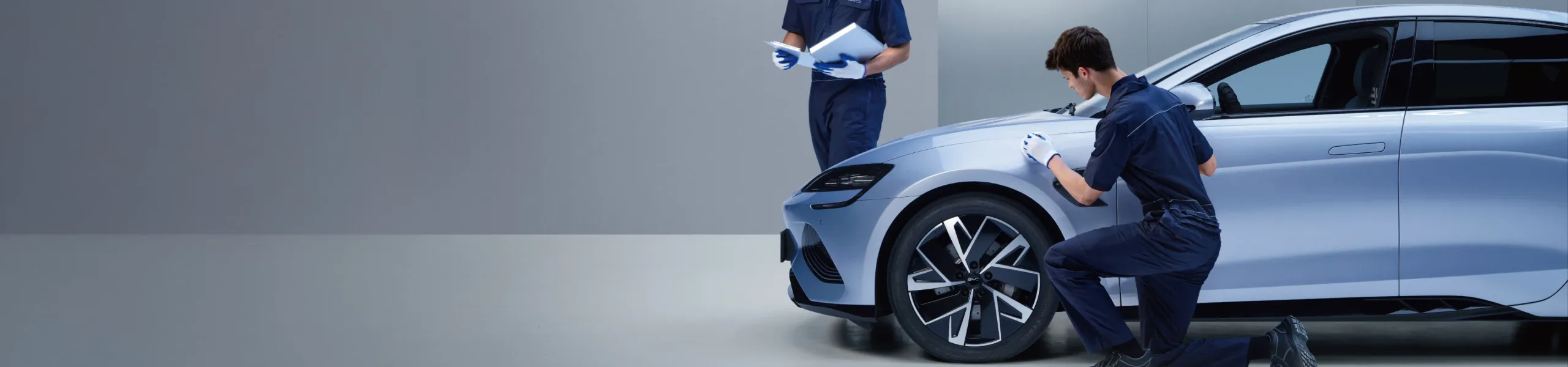 Dois técnicos da BYD Service analisam detalhes do BYD para avançar com a manutenção do carro elétrico.