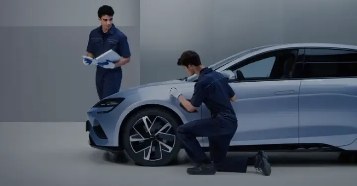 Dois técnicos da BYD Service analisam detalhes do BYD para avançar com a manutenção do carro elétrico.