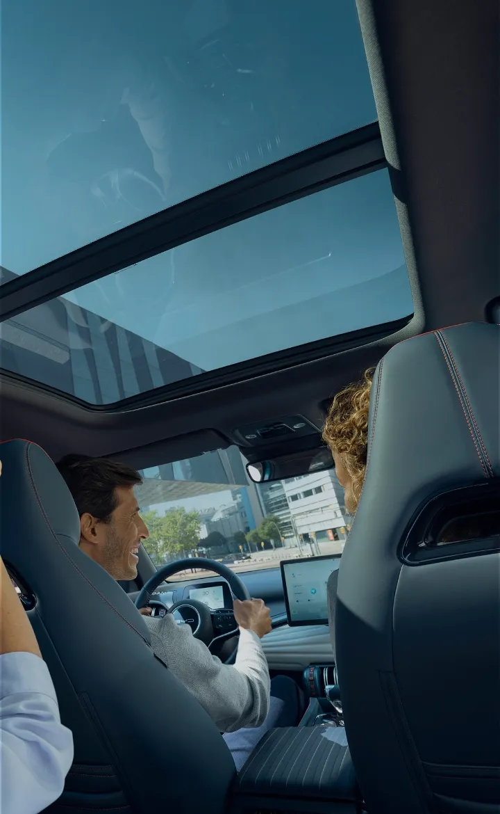Pessoas com aspeto feliz, no interior de um BYD, onde se vê a pessoa que vai sentada no banco traseiro, a apontar para o teto panorâmico