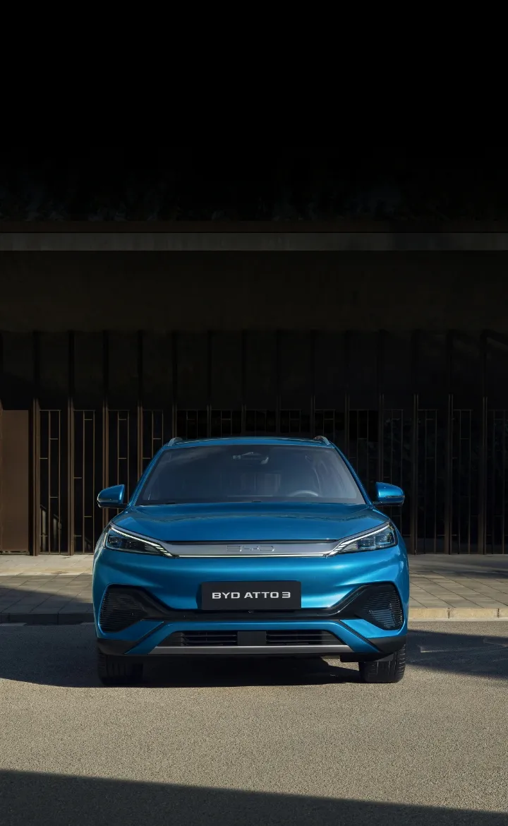 Visão frontal do BYD ATTO 3 estacionado ao pé de um portão