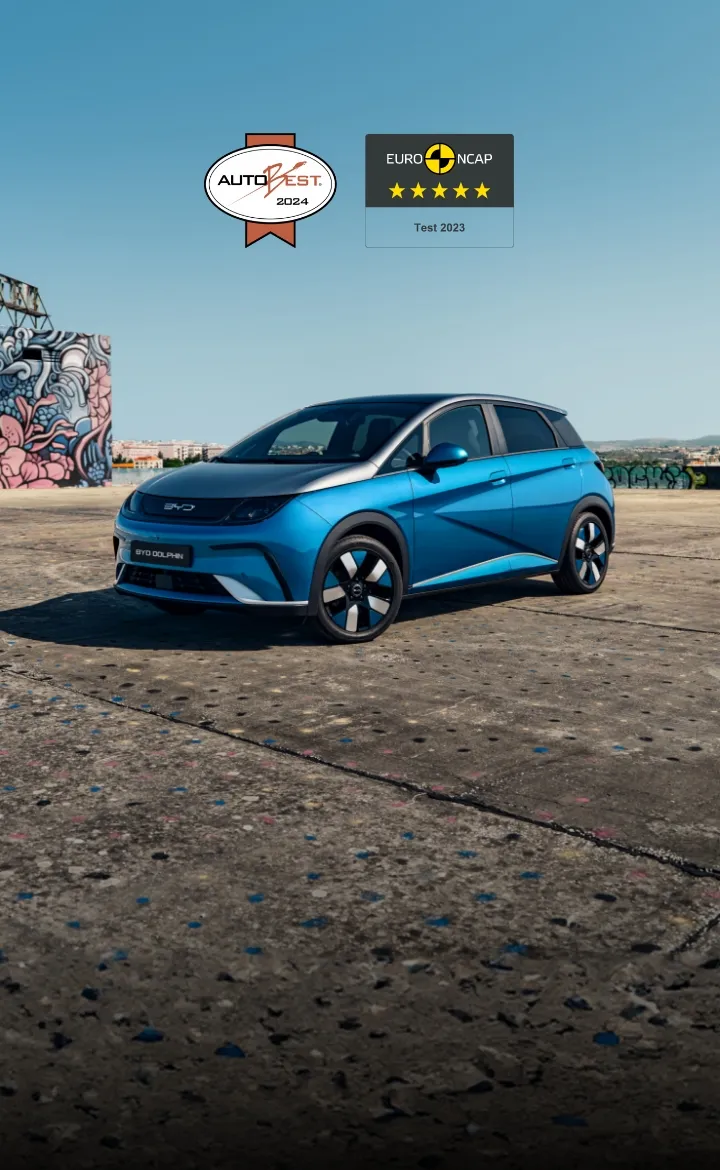 Vista a três quartos de um BYD DOLPHIN azul numa área de betão e com um bloco grafitado mais atrás