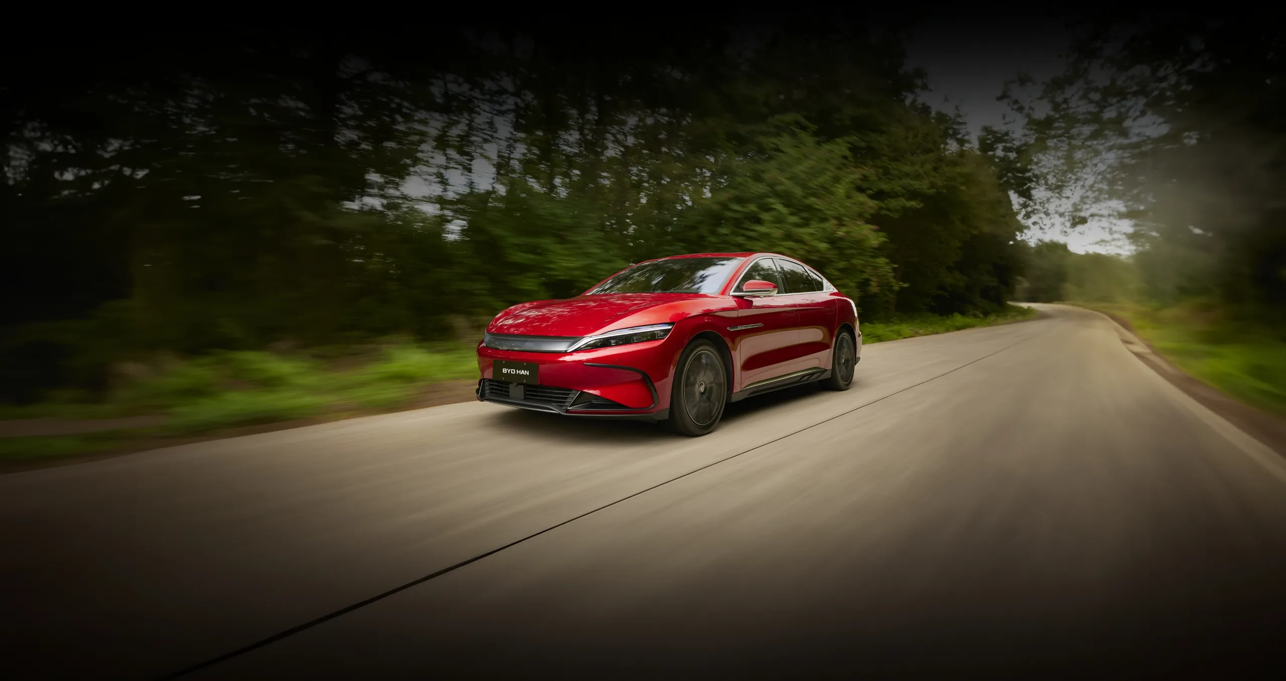 BYD HAN percorre estrada no campo ladeada por árvores