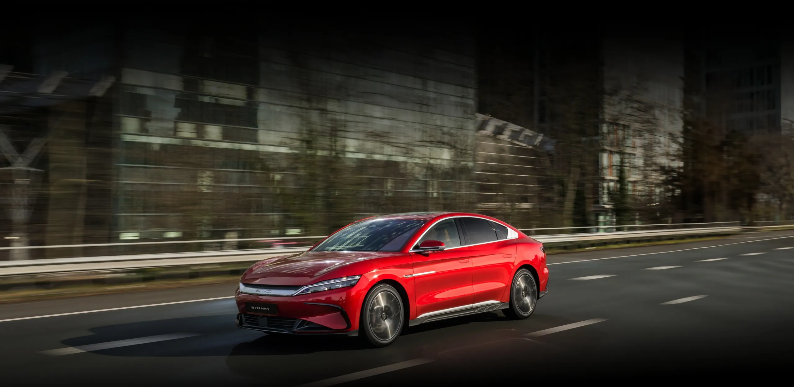 BYD HAN percorre as ruas de uma cidade com edifícios espelhados