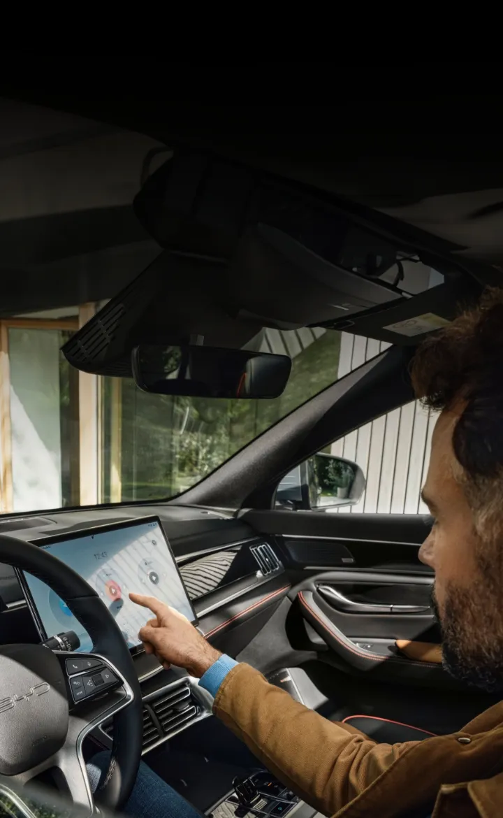 Condutor no cockpit do BYD SEAL U DM-i digita algo no ecrã LCD de infoentretenimento