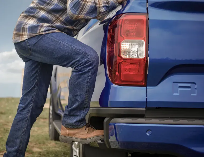 Pessoa a subir para a caixa traseira da Ford Ranger através do degrau que ela tem