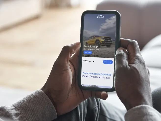 Telefone na mao de uma pessoa com o site da ford aberto