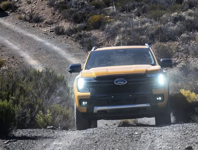 Ford Ranger a andar por uma estrada de terra com as luzes ligadas