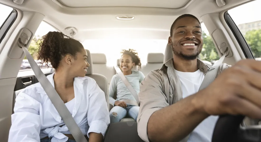 Familia de 3 pessoas contentes a andar no seu veiculo